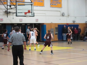 Both teams wait in anticipation for the ball to go through the hoop